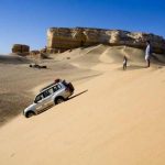 4x4 jeep driving over sand dunes in the Western Desert near the White Desert