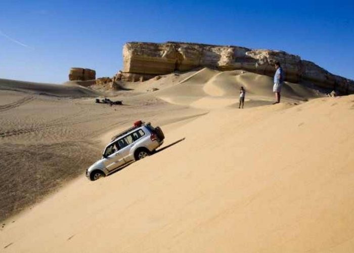 4x4 jeep driving over sand dunes in the Western Desert near the White Desert