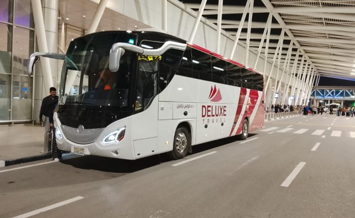 Deluxe Travel Egypt coach at an airport terminal for a group airport transfer