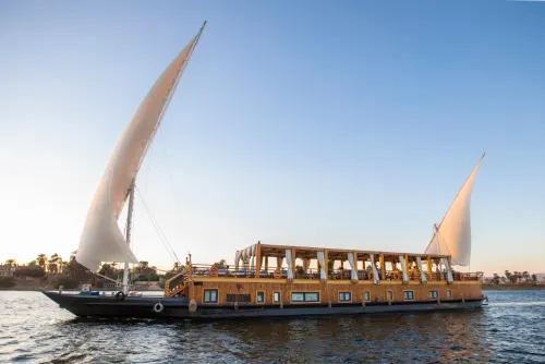 Dahabiya under full sail on the Nile Traditional dahabiya boat under full sail on the Nile at sunset