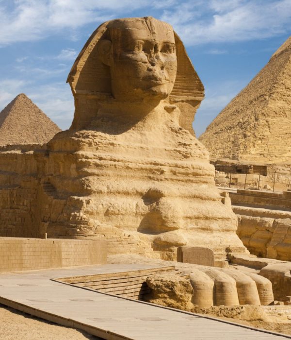 The Great Sphinx of Giza with the pyramids of Khafre and Khufu under a blue sky