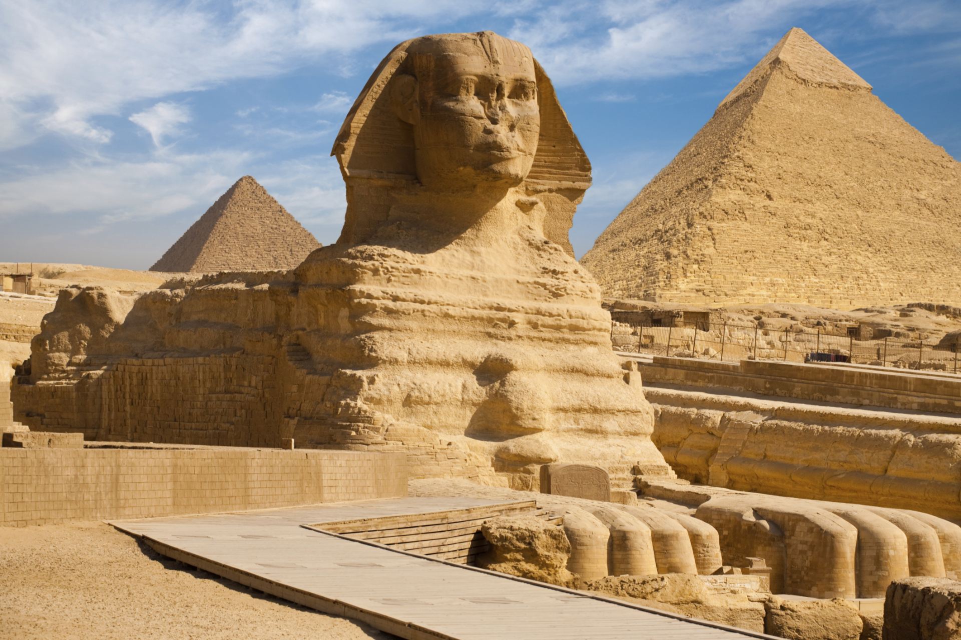 The Great Sphinx of Giza with the pyramids of Khafre and Khufu under a blue sky